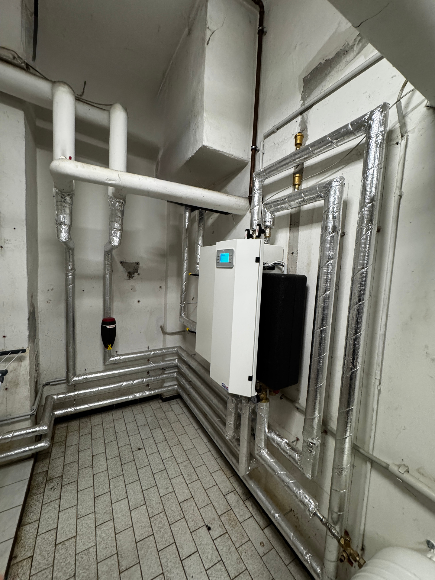 Frisch installierte Heizungsanlage im Technikraum mit isolierten Rohrleitungen